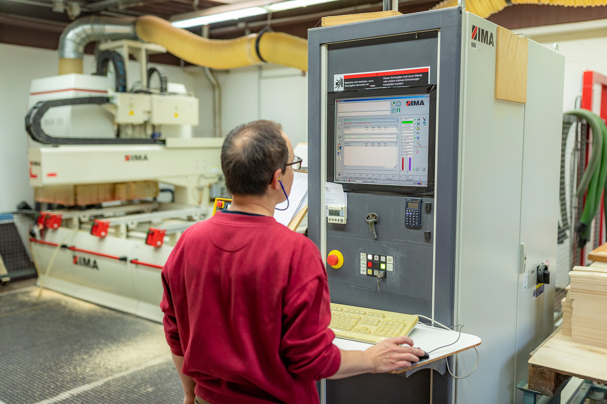 Mann am Bedienfeld für CNC-Maschine Mann am Bedienfeld für CNC-Maschine